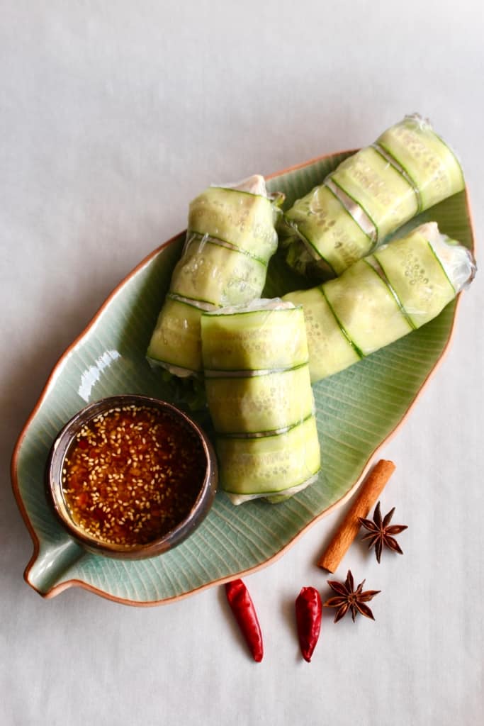 Summer rolls on a leaf-shaped dish with spices scattered next to it.