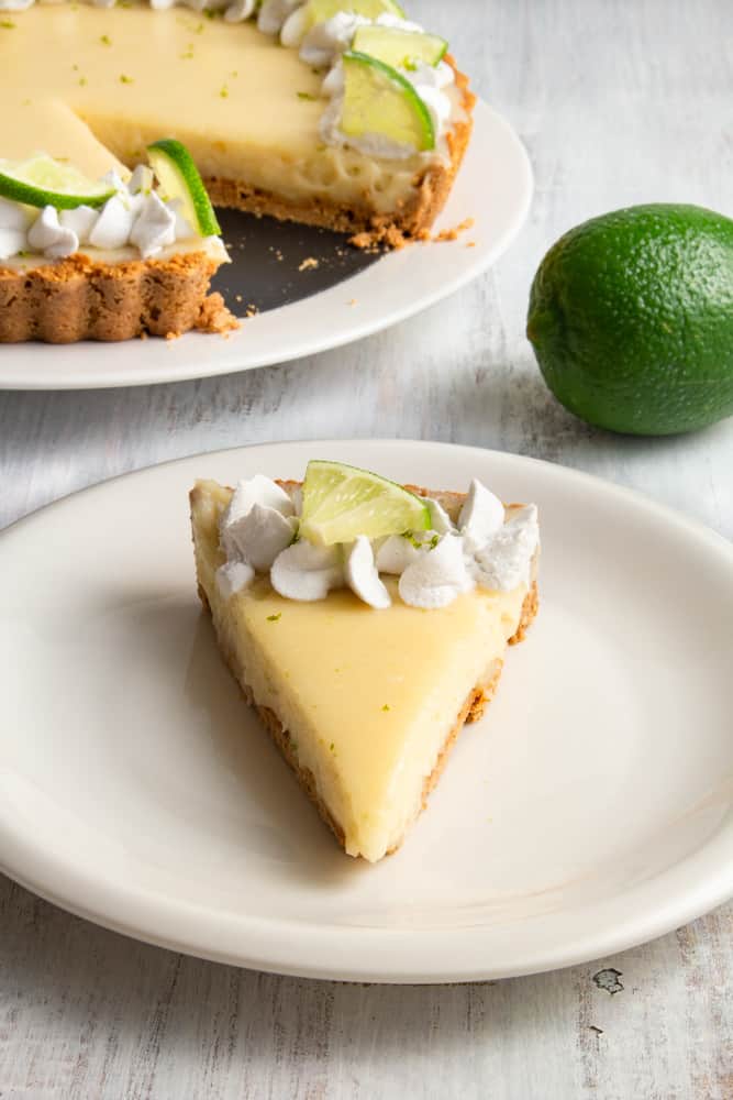 This vegan key lime pie is so creamy and tangy! With a crunchy graham cracker crust on the bottom and topped with rich coconut whipped cream, this plant based dessert won’t have you missing the traditional key lime pie! #vegandessert #vegankeylimepie #keylimepie #nobakedessert #nobakepie #plantbaseddessert