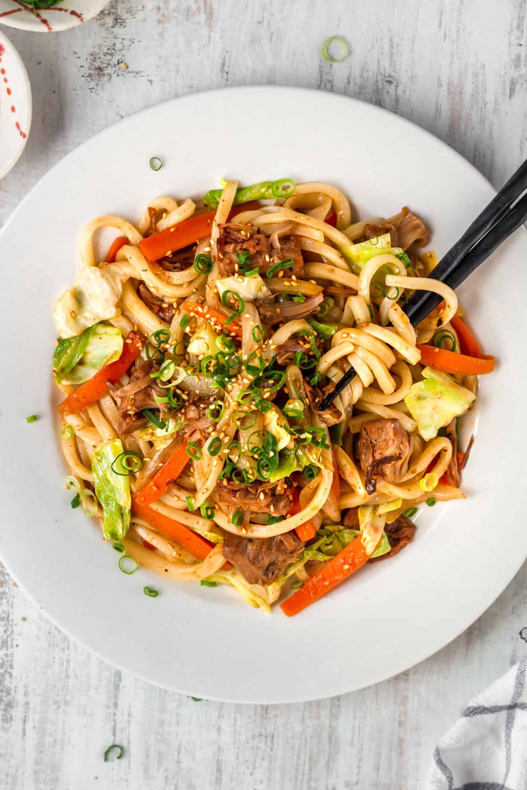 A plate of spicy noodles with black chopsticks