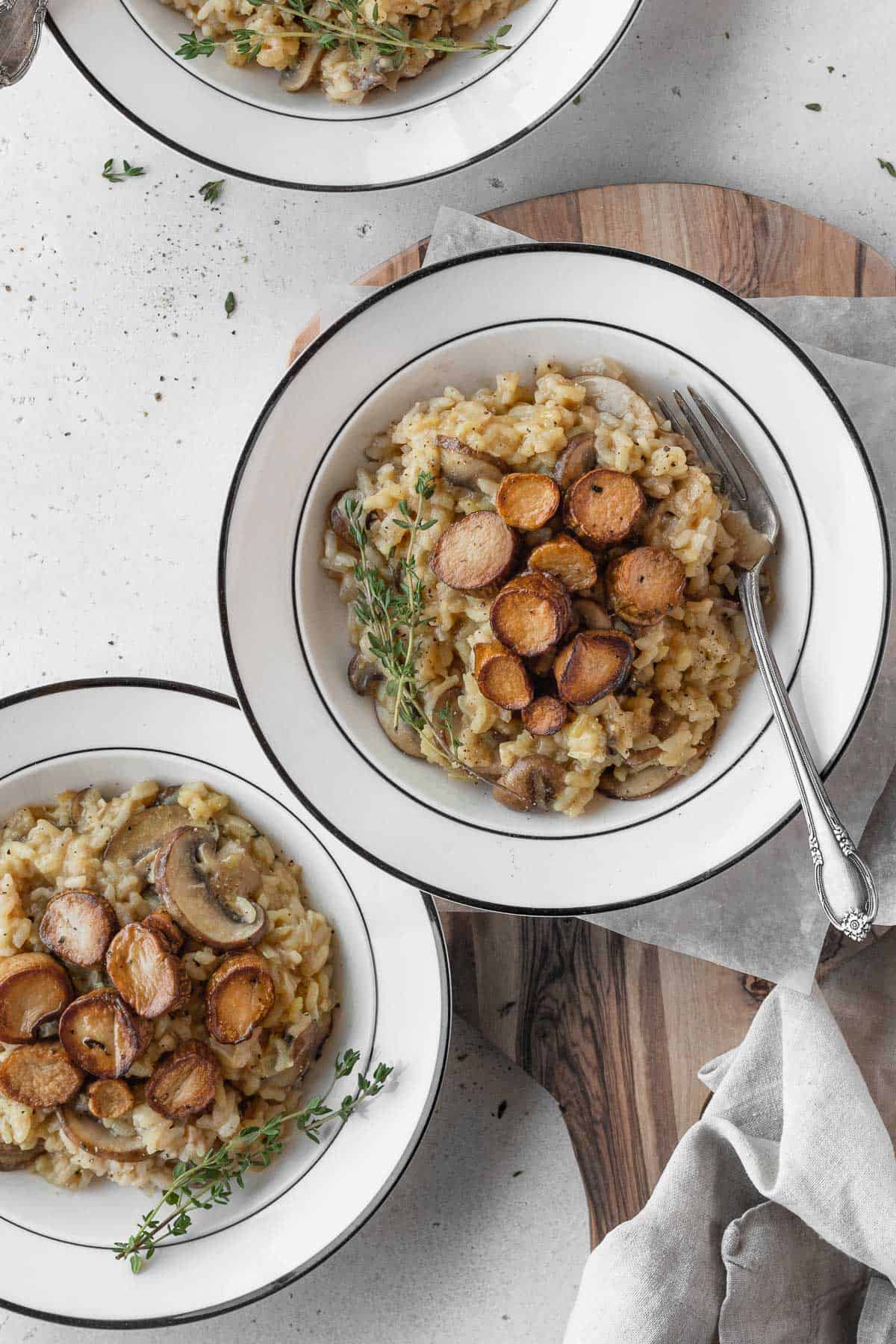 Vegetarian risotto with mushrooms in white bowls.