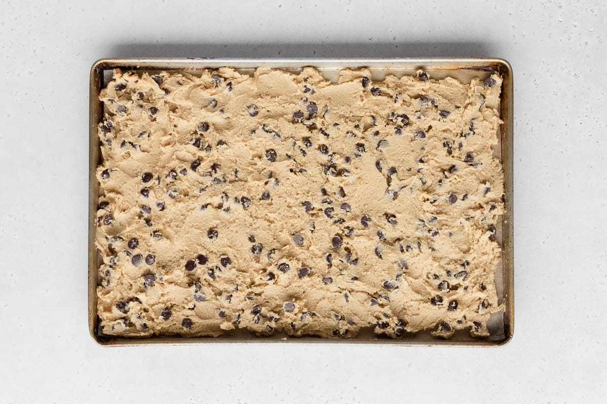entire batch of boxed cookie dough spread out into a layer across a sheet pan. 