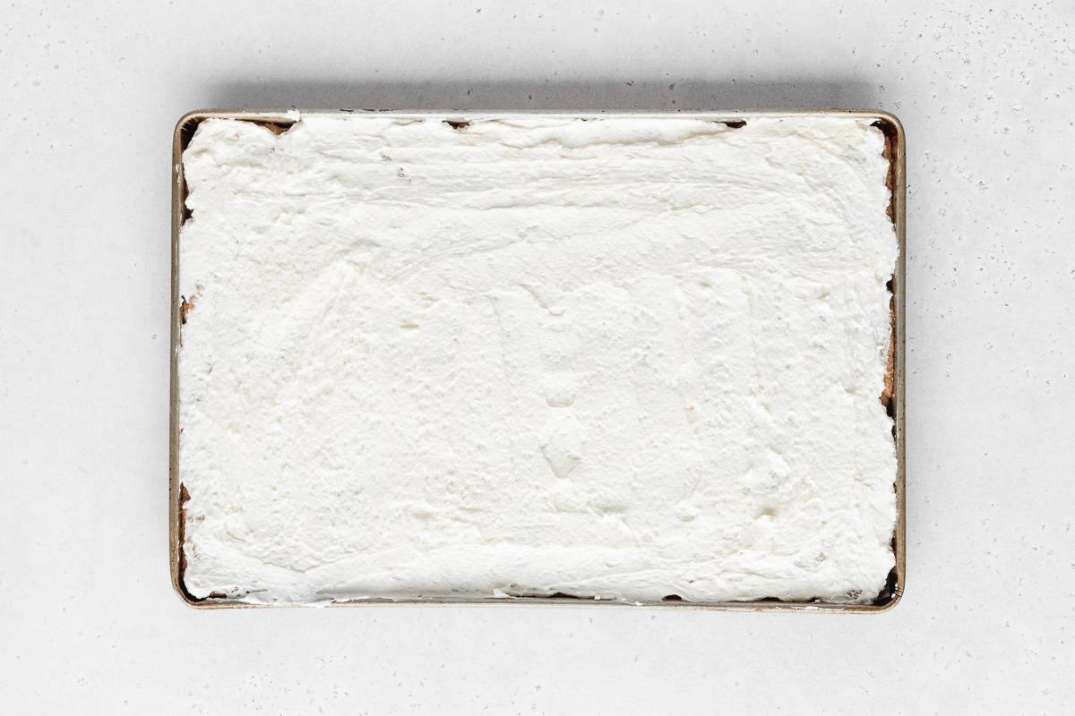 white cream cheese frosting spread over the entirety of the sheet pan cookie. 
