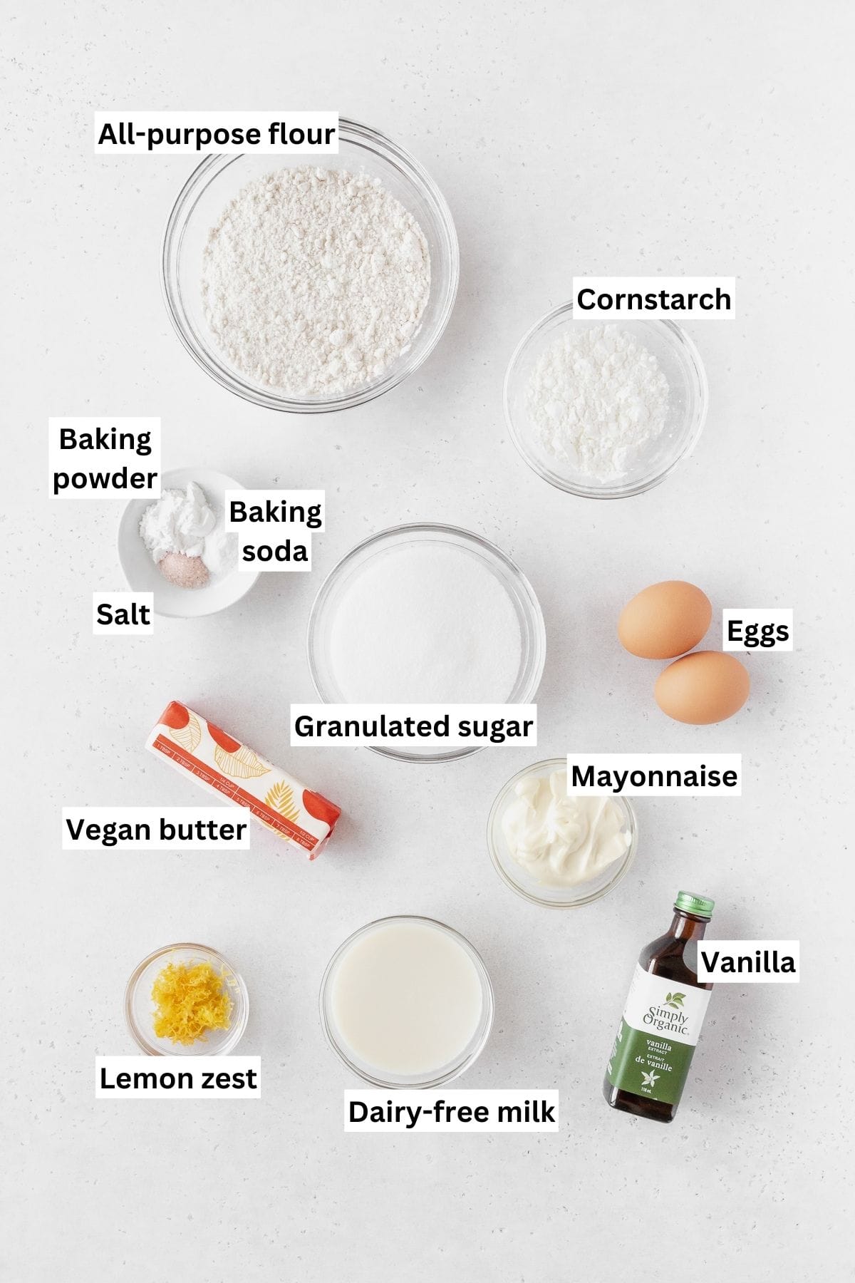 Ingredients needed for making lemon curd cake recipe on a white table with text overlay.