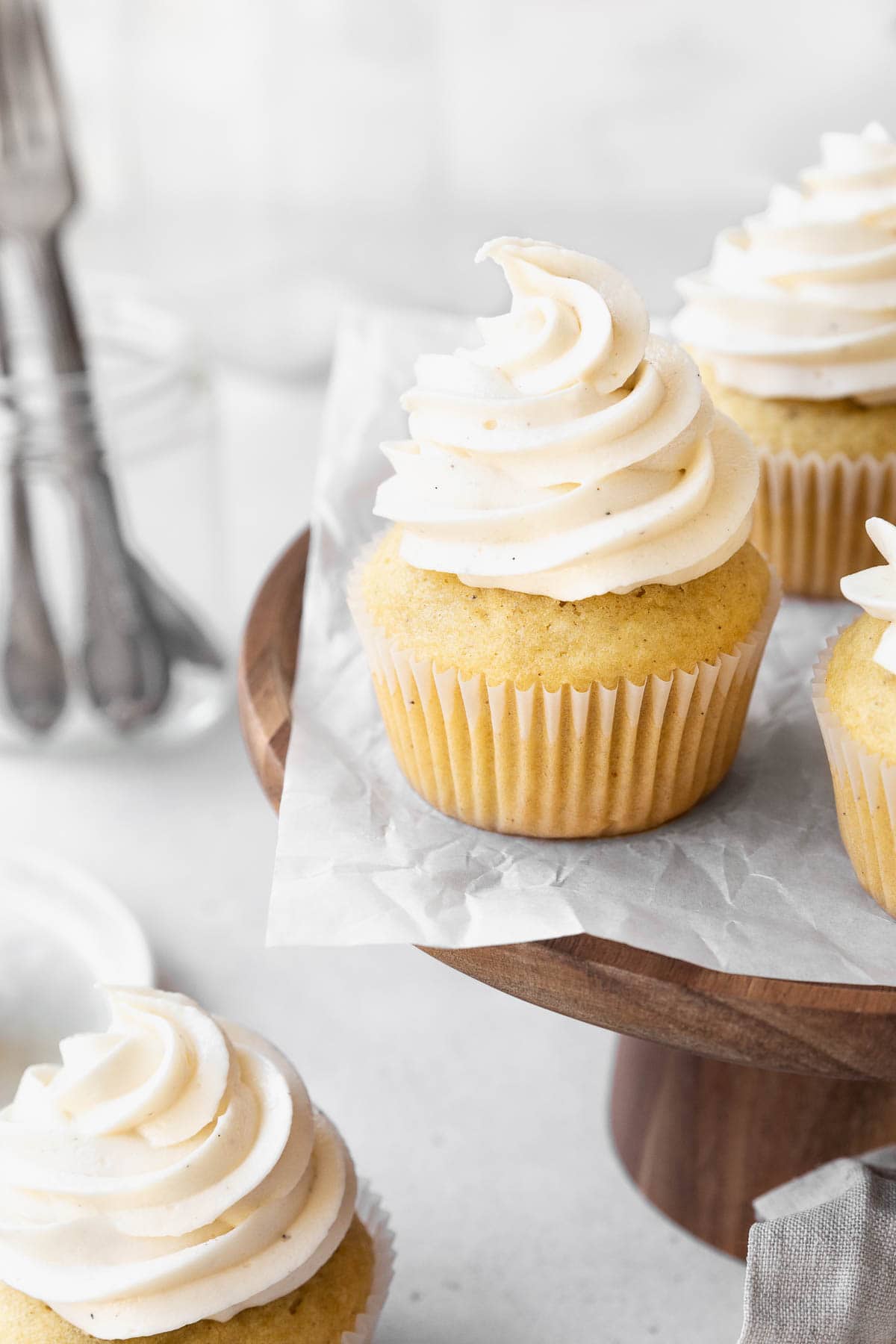 Wooden cake stand with dairy-free buttercream topped vanilla cupcakes.