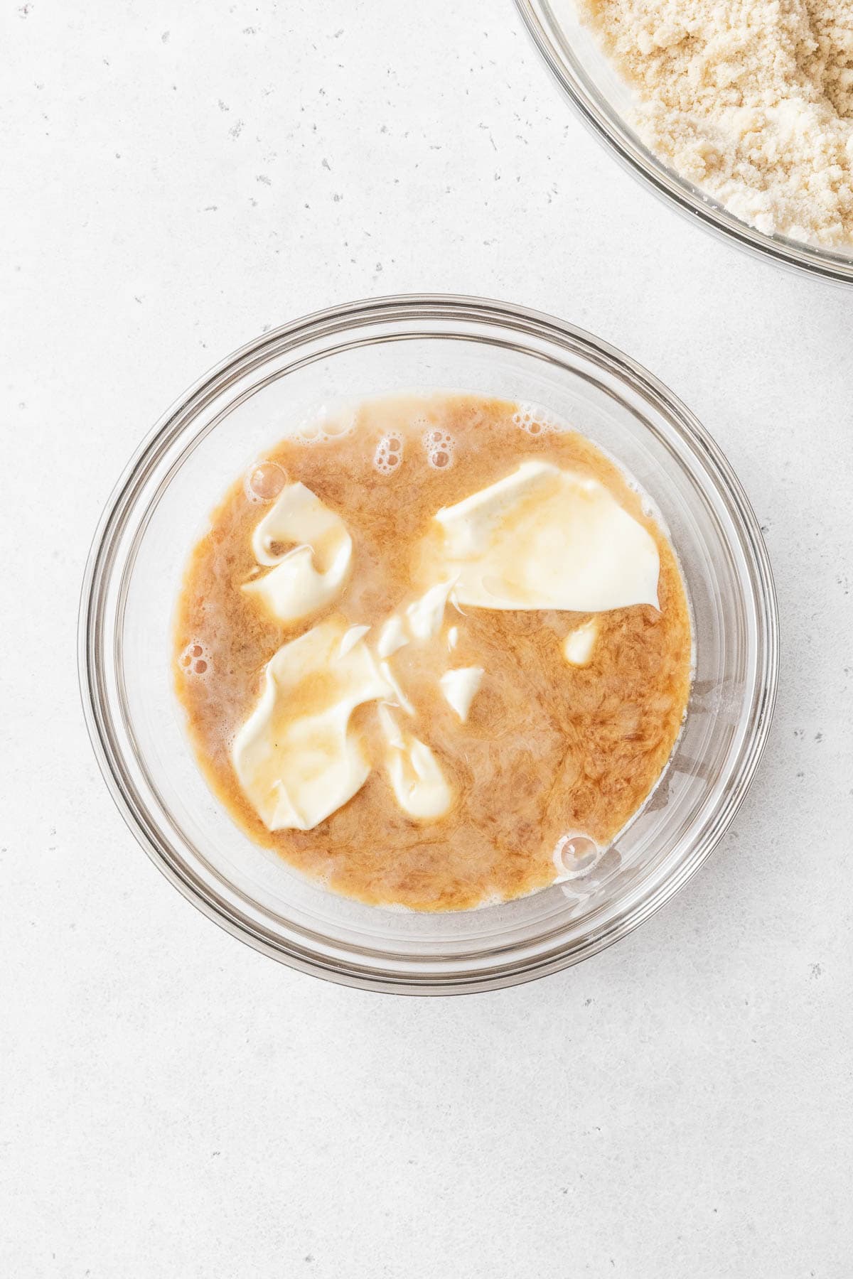 A glass mixing bowl of milk, vanilla, and mayonnaise.