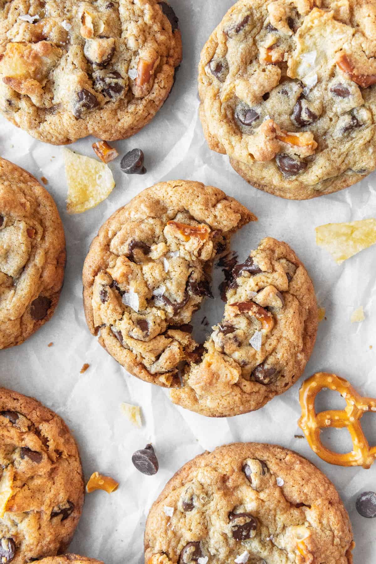 A everything but the kitchen sink cookie broken in half with more cookies scattered around.